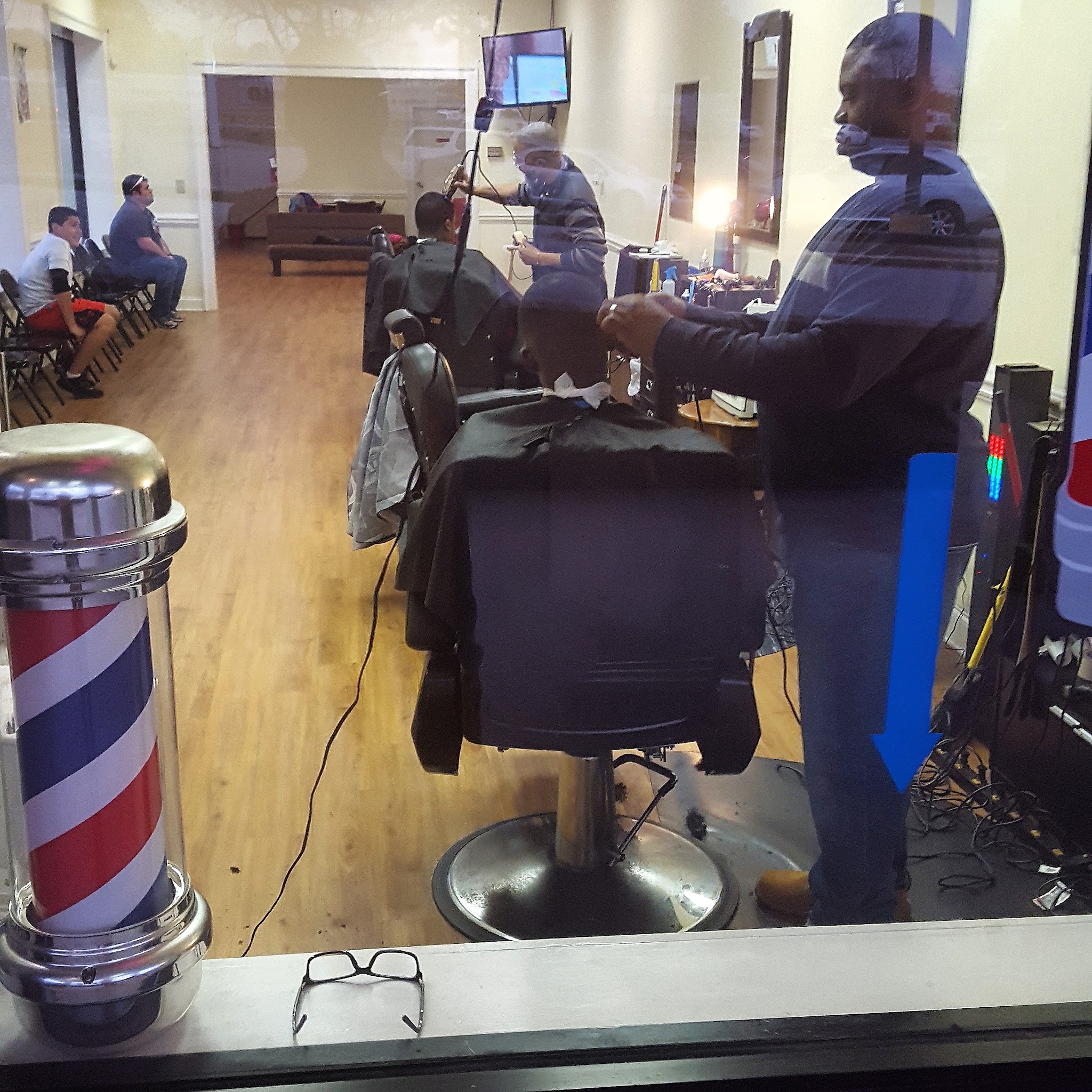 A barber at work in the chair, with the barber pole in the window